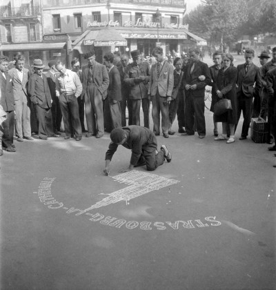 Pierre Soulier, *Enquête sur Robert Eberlé, dessinateur sur trottoirs*, Robert Eberlé dessinant à la craie sur trottoir la cathédrale de Strasbourg à l’angle des boulevards de Strasbourg et de Magenta à Paris, France, Paris, 8 août 1945, Reproduction à partir de négatifs souples © Mucem