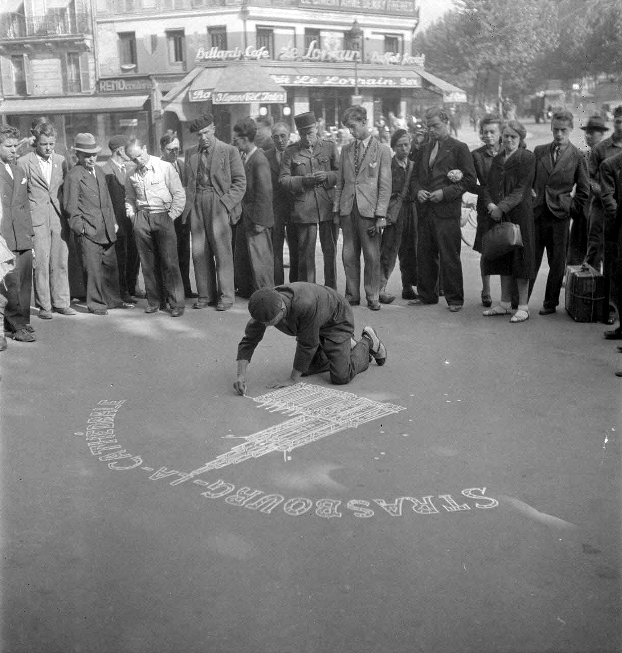 Pierre Soulier, *Enquête sur Robert Eberlé, dessinateur sur trottoirs*, Robert Eberlé dessinant à la craie sur trottoir la cathédrale de Strasbourg à l’angle des boulevards de Strasbourg et de Magenta à Paris, France, Paris, 8 août 1945, Reproduction à partir de négatifs souples © Mucem