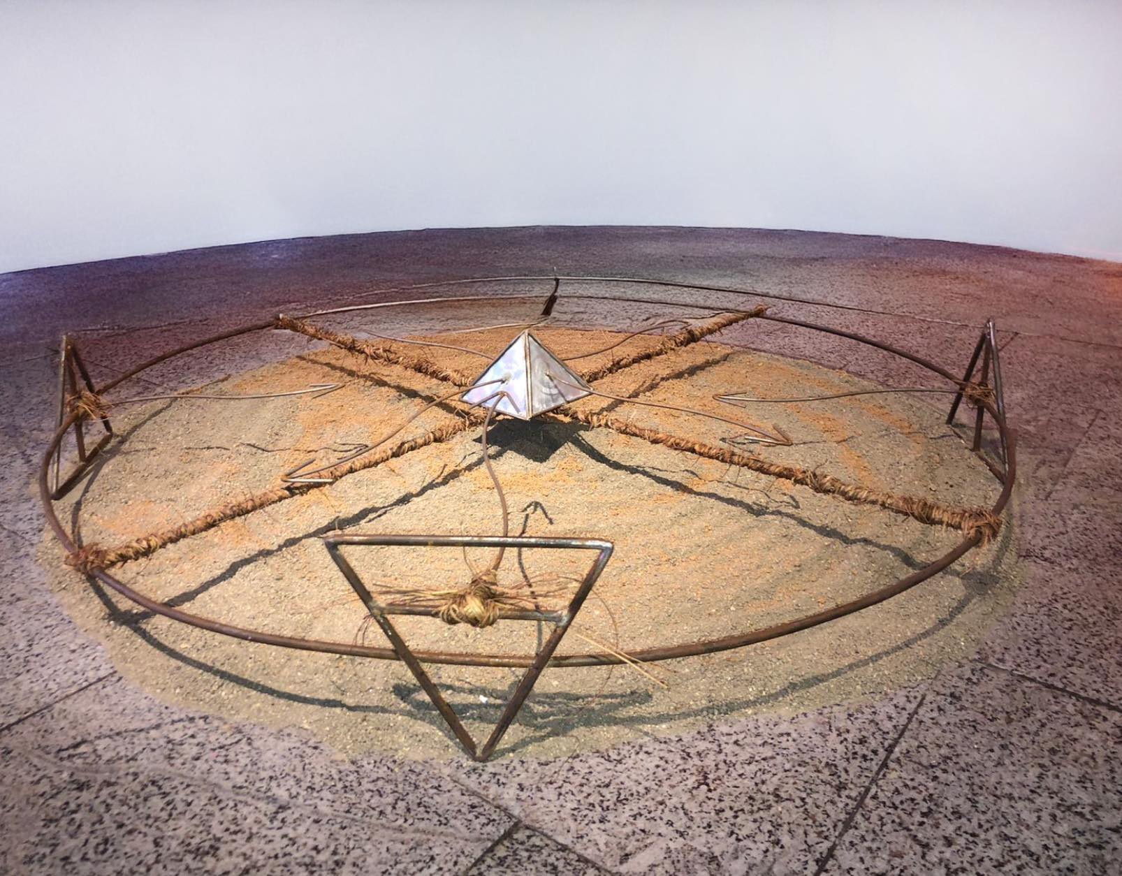 Gira X, Installation, 2024. Acier, lianes, terre noire et rouge. Sculpture, 120 x 120 cm. Pliage, soudure et ligature.